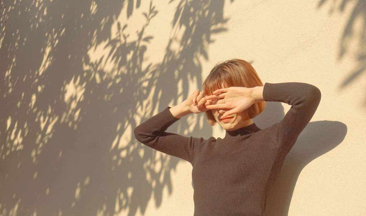 一位女孩用手遮擋陽光，減少皮膚光老化的現象